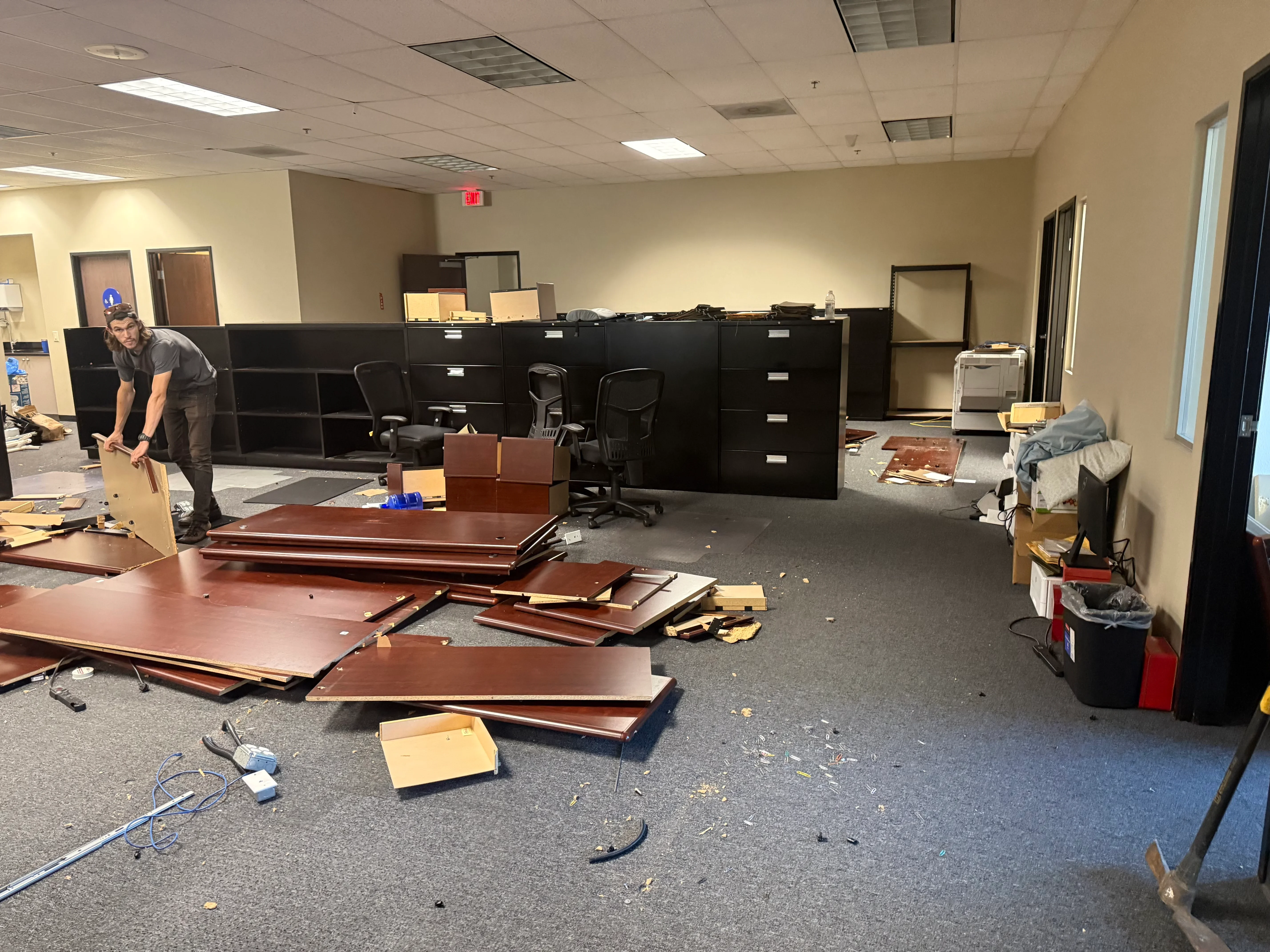 Commercial office interior demolition with black cabinetry and wooden furniture removal in progress