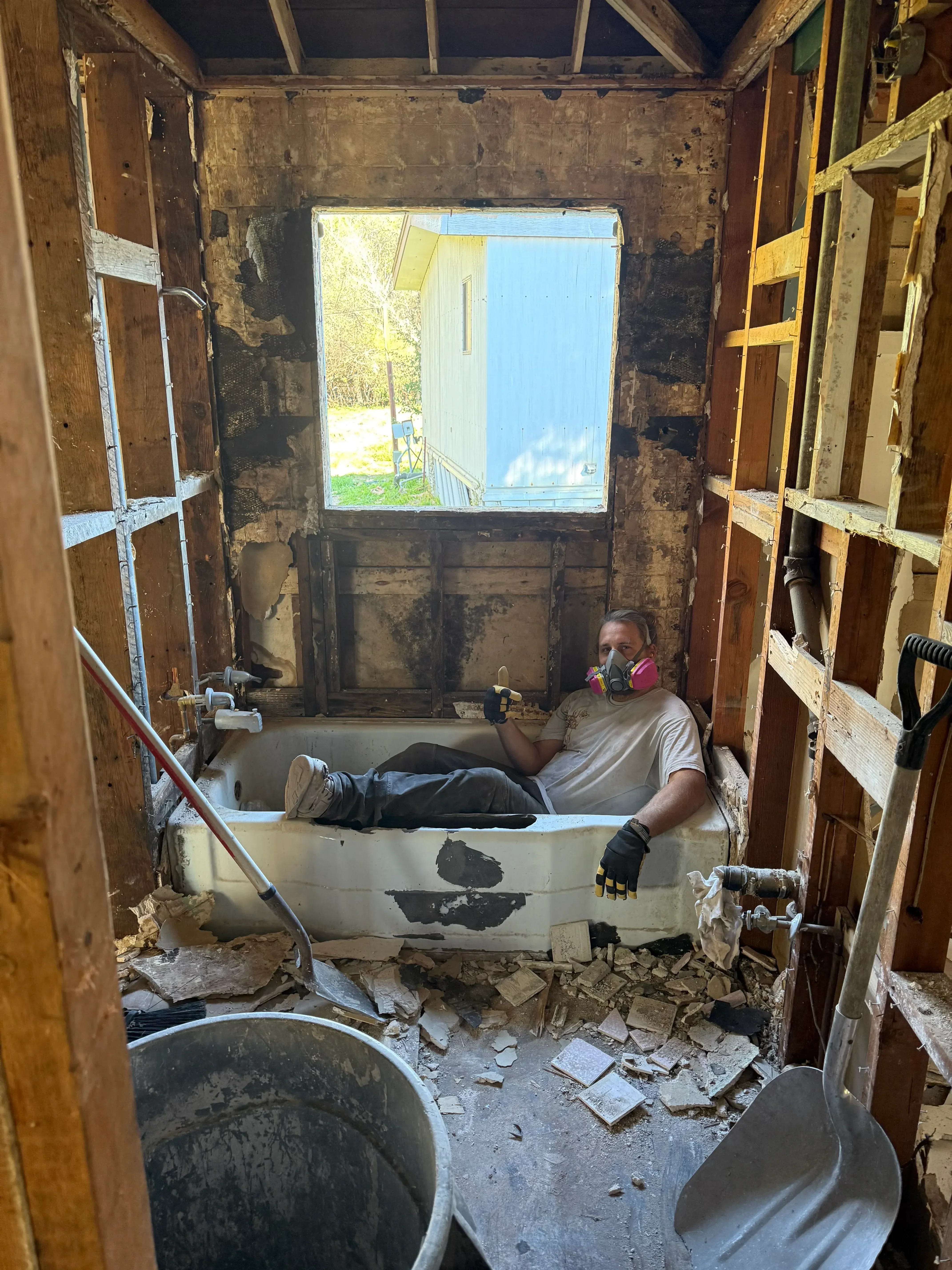 Interior demolition with exposed wood framing, drywall removal, and debris staging