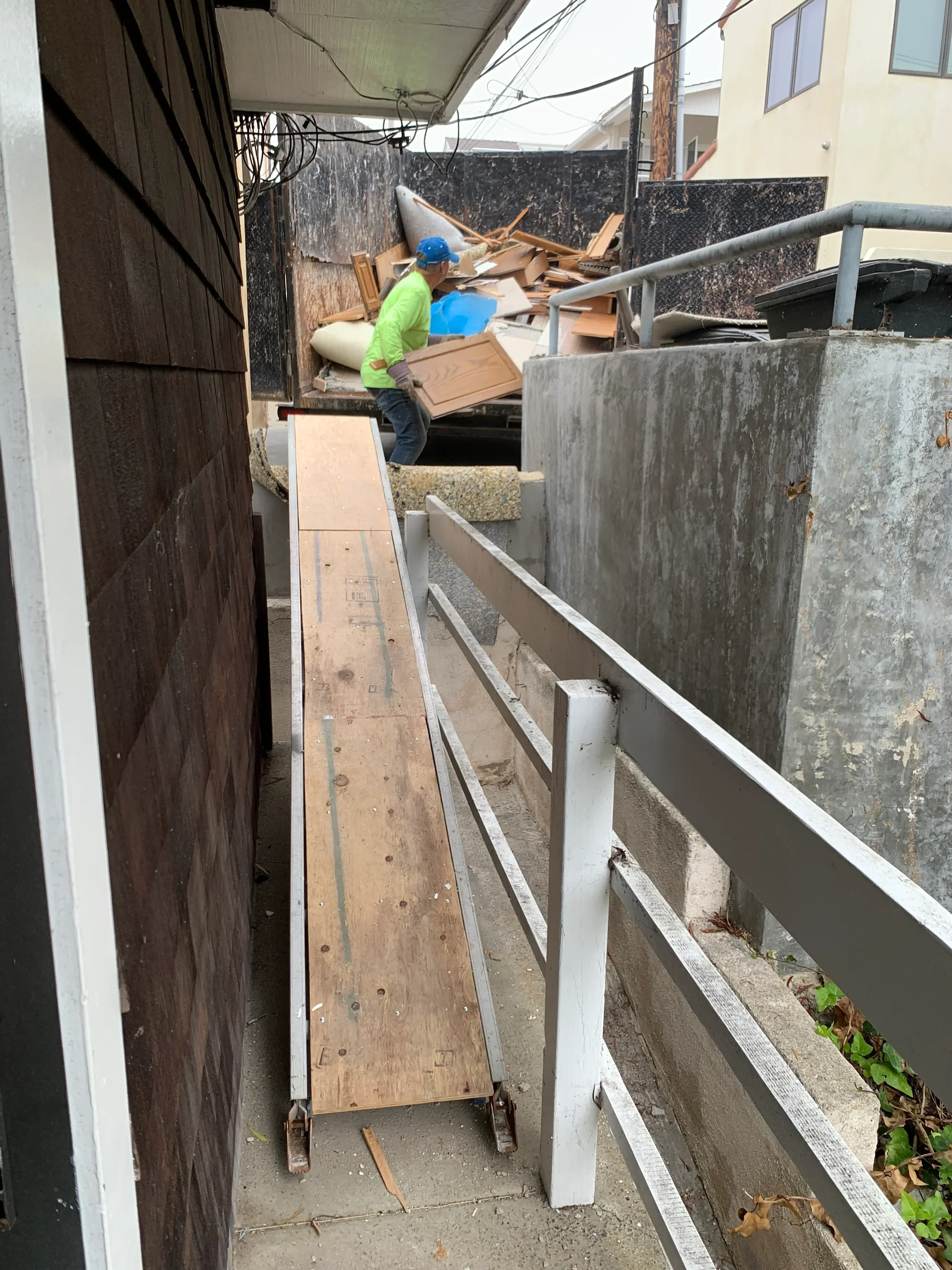 Concrete foundation demolition with metal beams and wooden framing removal in progress